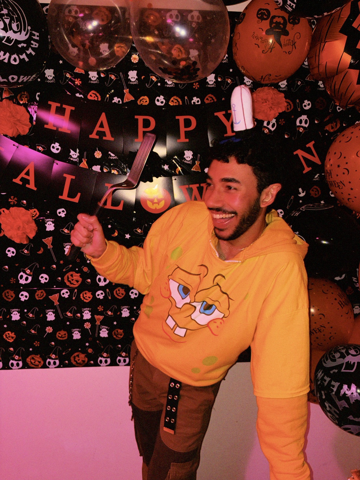 Mat laughing at his Halloween birthday party, holding a giant kitchen utensil